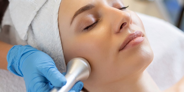 Junge Frau liegt während der Verjüngungskur auf dem Tisch der Kosmetikerin.